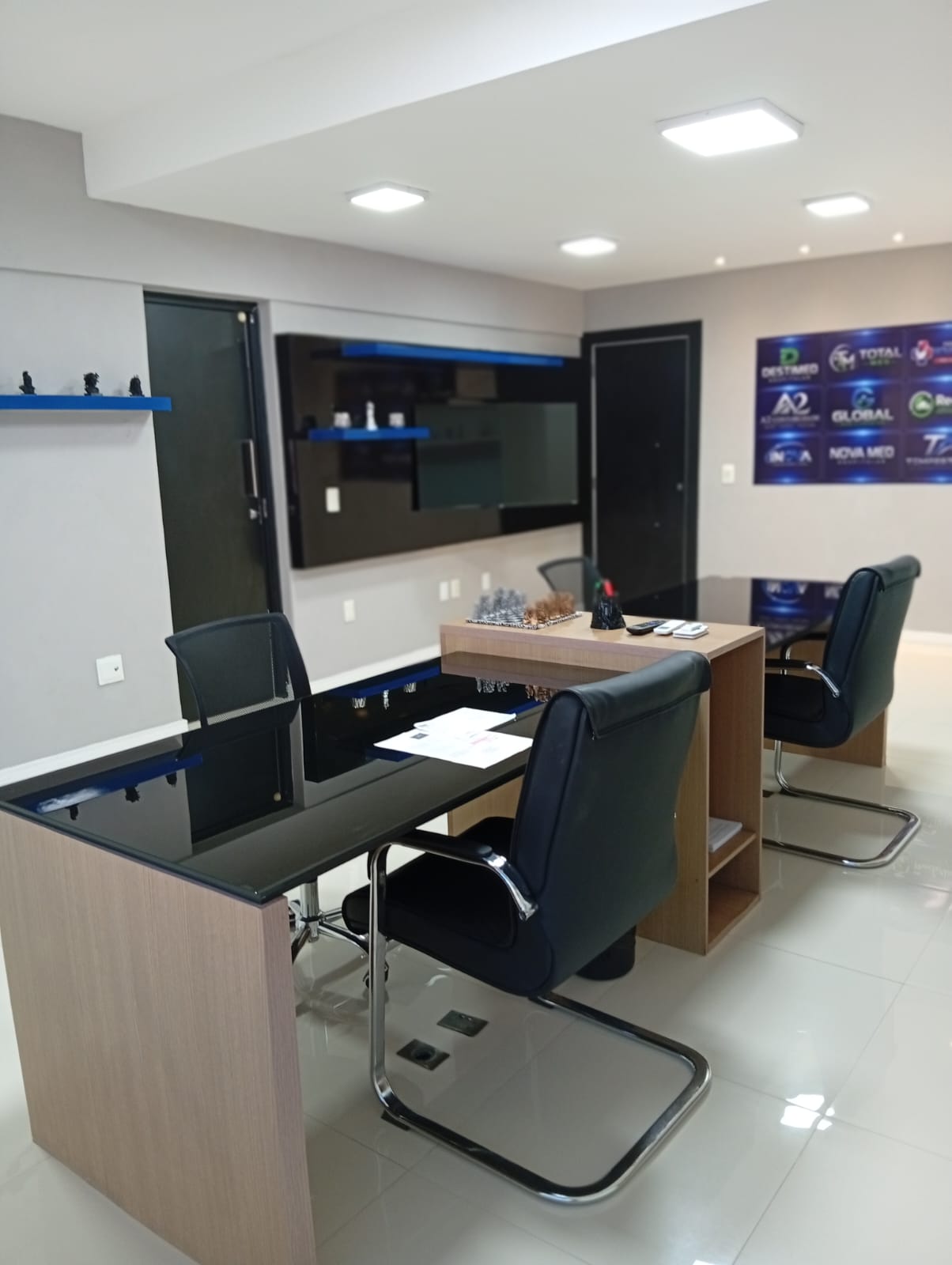 Outro ângulo da sala de atendimento, com mesas e cadeiras